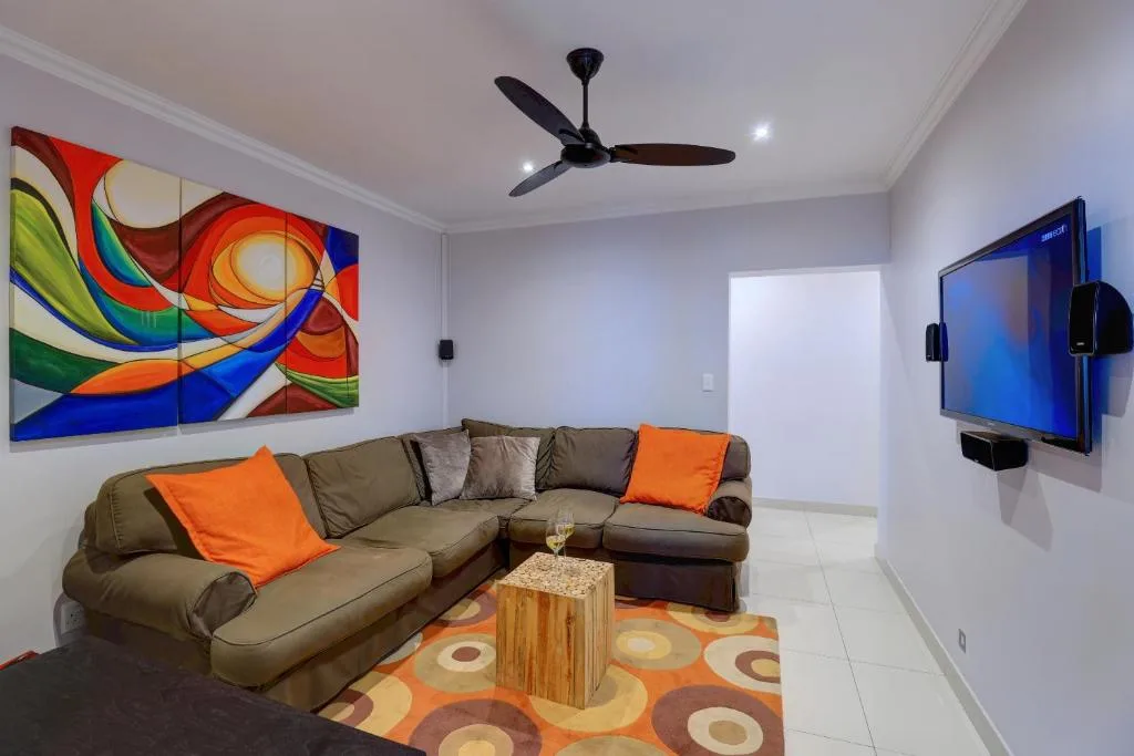 Modern lounge with sectional sofa, colorful artwork, and wall-mounted television