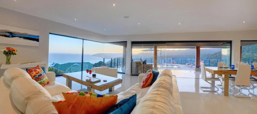 Modern lounge with panoramic coastal and mountain views through floor-to-ceiling windows