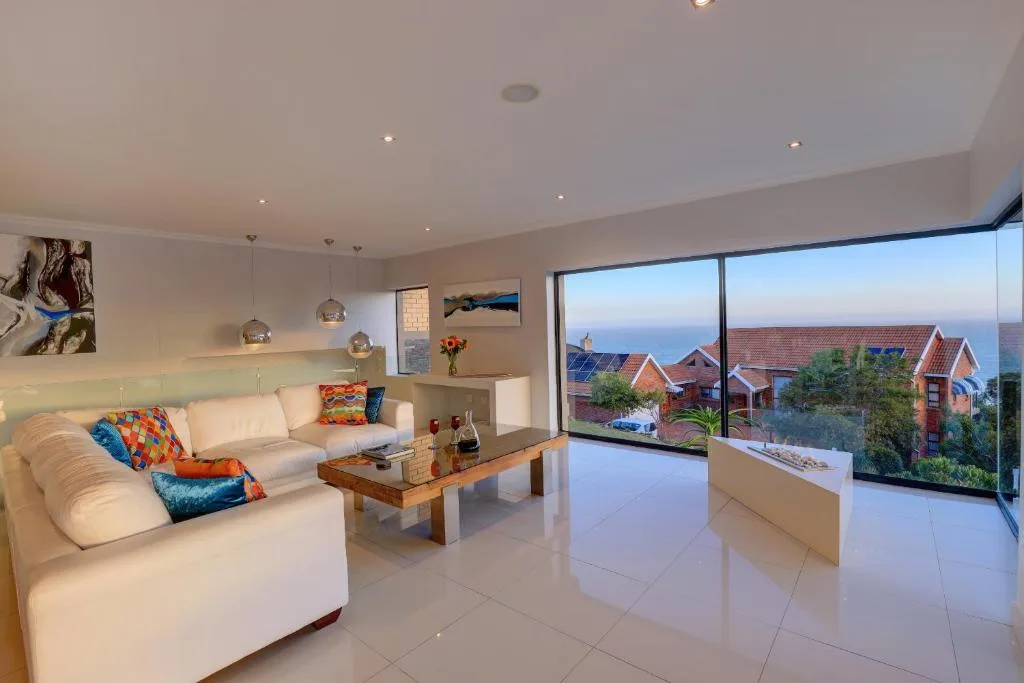 Bright open-plan lounge with cream sofas and coastal views through large windows
