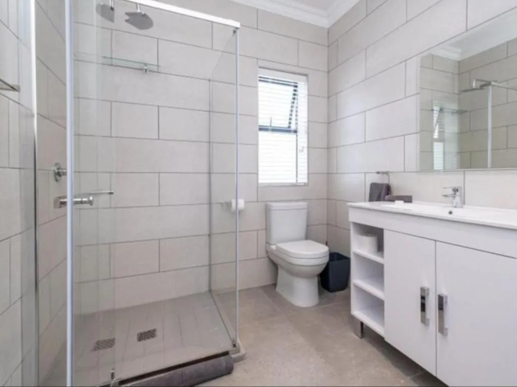 Modern white bathroom with glass shower enclosure and vanity sink