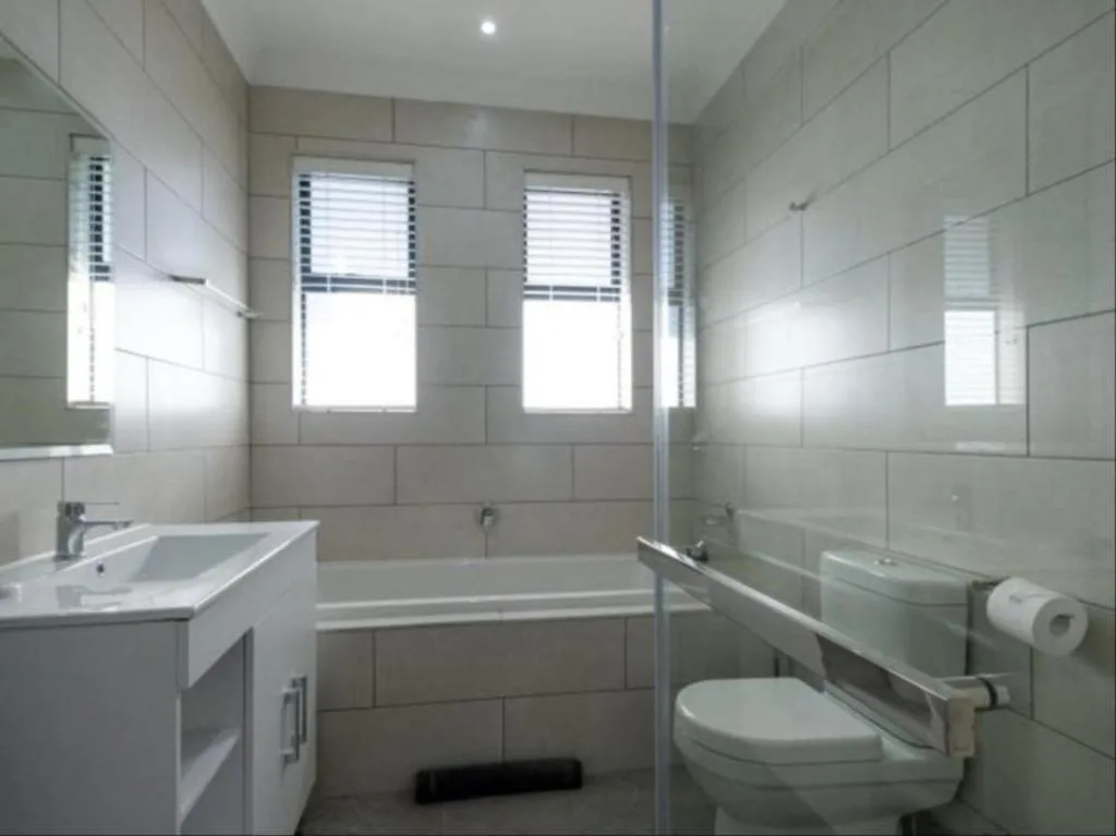 Modern bathroom with white subway tiles, sink vanity, toilet, and bathtub