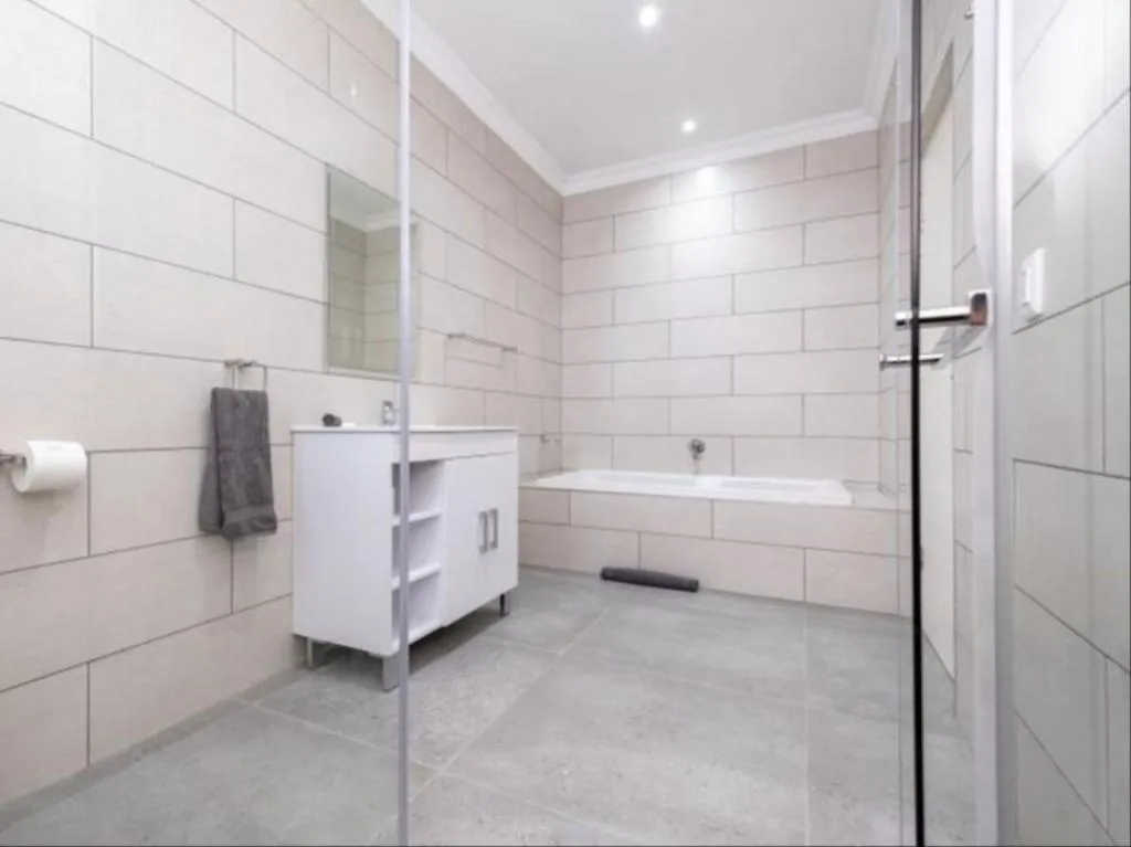 Modern bathroom with white vanity, walk-in shower, and bathtub