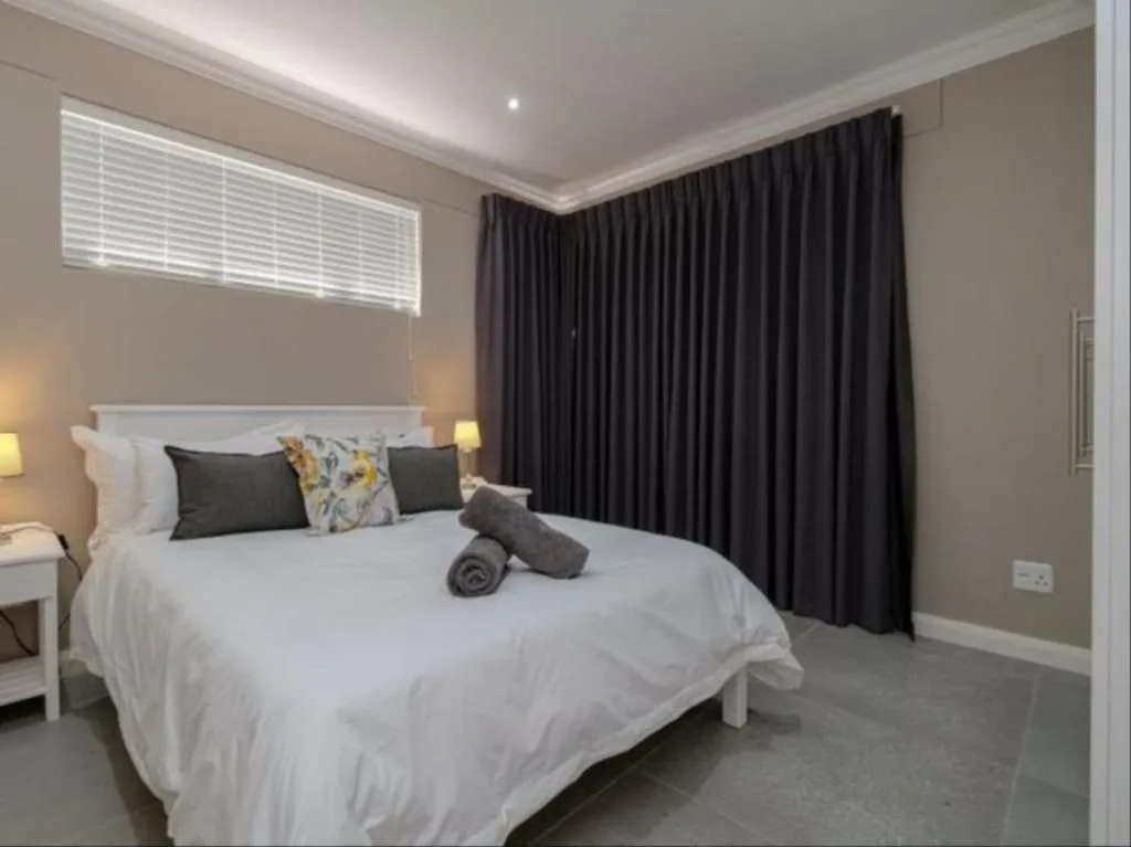 Modern bedroom with white bed, dark curtains, and contemporary decor
