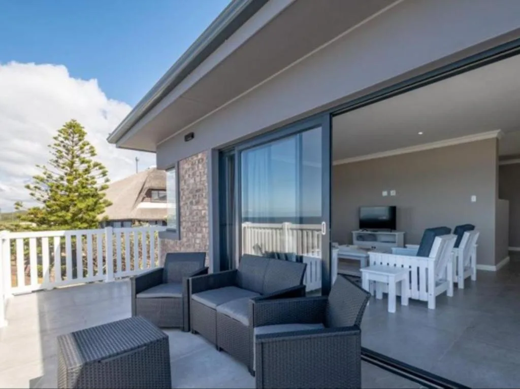 Modern outdoor patio with seating, railing, and views toward interior