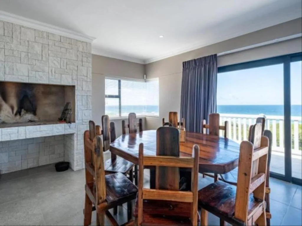 Spacious dining room with wooden table, ocean view through glass doors