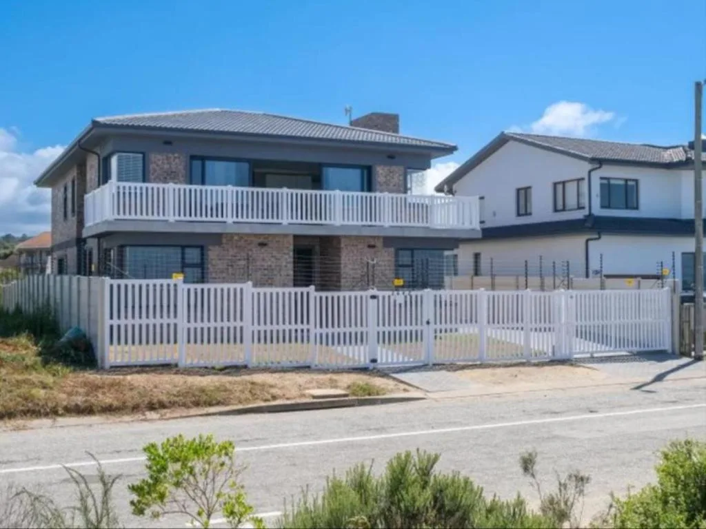 Modern two-story residential building with white railings and brick facade on Garden Route