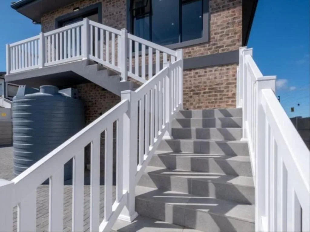 Modern brick home exterior with white railings and concrete stairs leading upward
