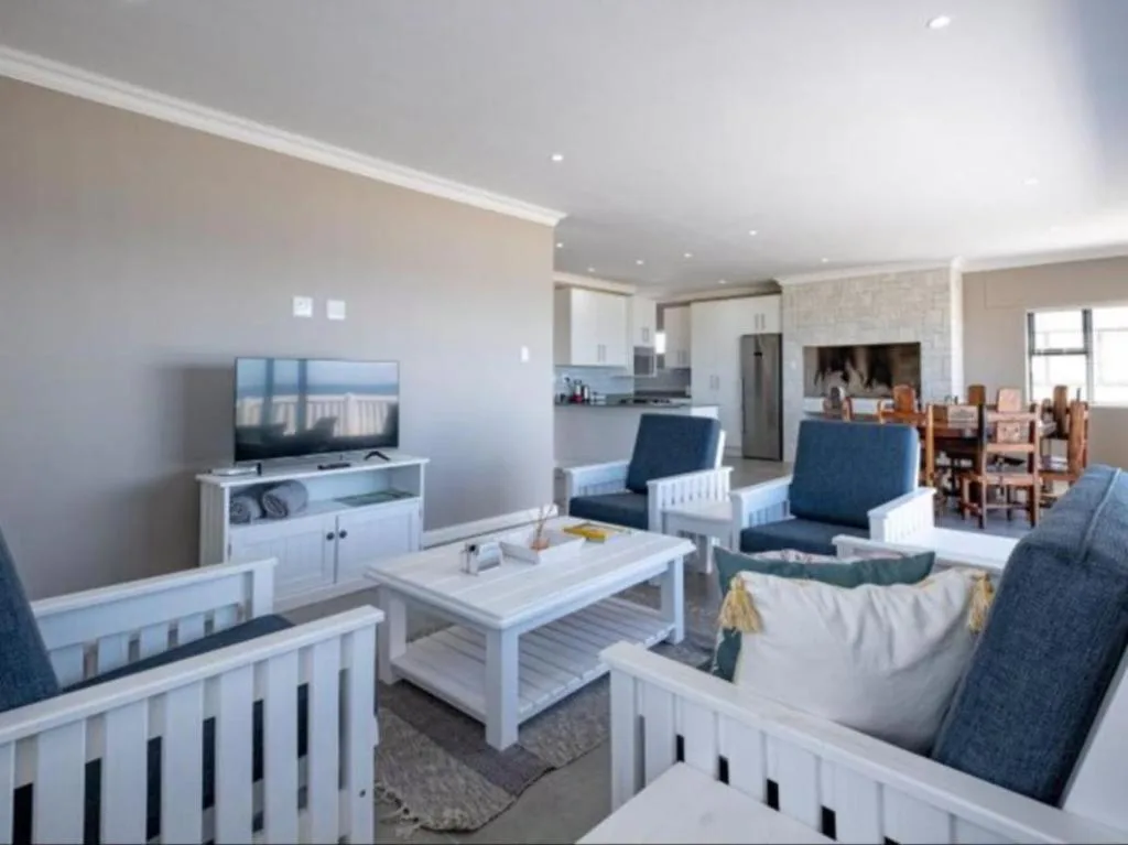 Open-plan lounge with TV, sofas, and kitchen visible in background