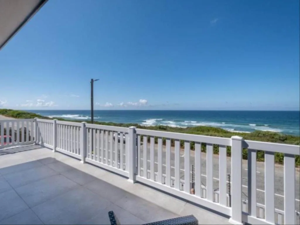 Ocean view from beachfront deck with white railings and coastal landscape