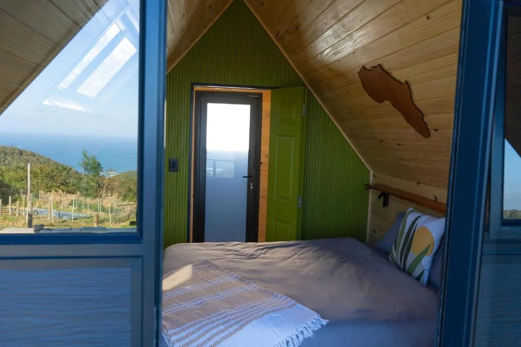Bright bedroom with double bed, green walls, wooden ceiling, ocean views
