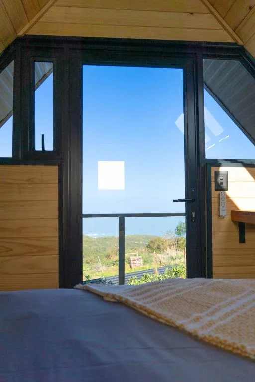 Bedroom with glass doors opening to scenic green valley landscape view