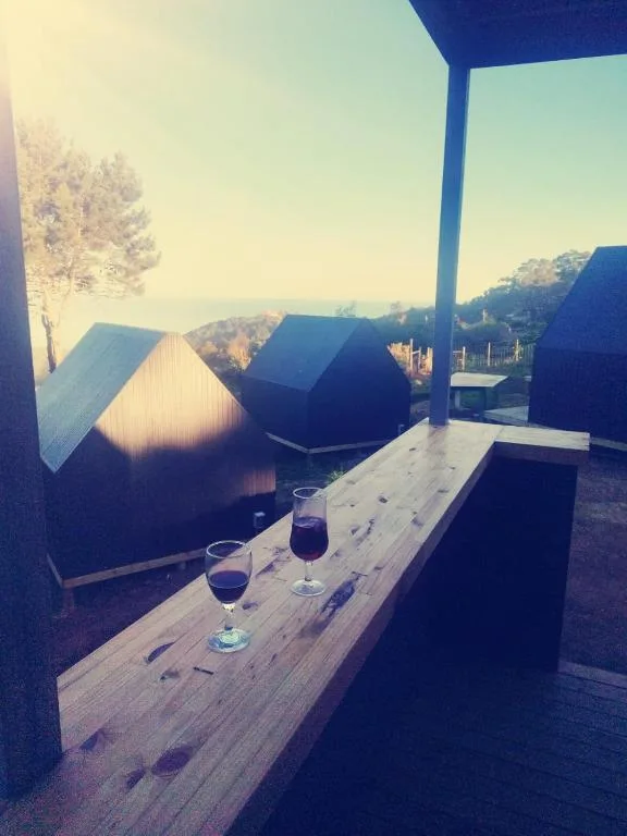 Wooden deck with wine glasses overlooking hillside landscape at sunset