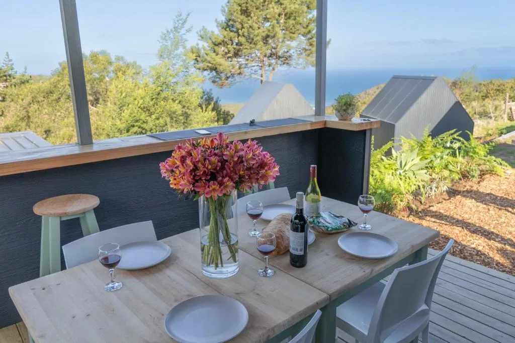 Outdoor dining table with ocean view, flowers, and wine glasses