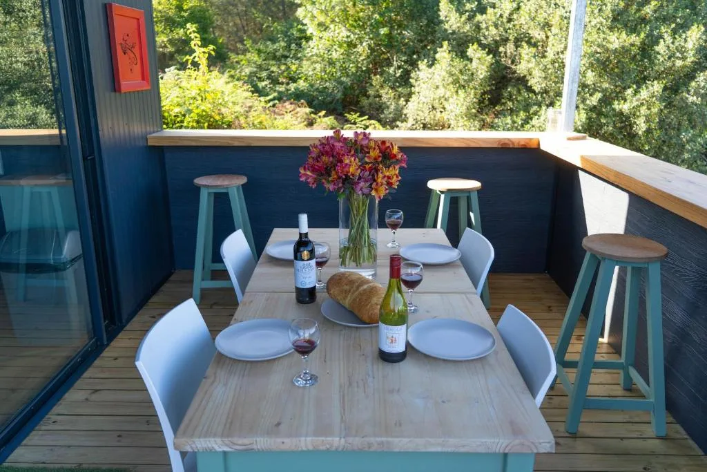 Outdoor dining setup with wooden tables and colorful flowers overlooking forest
