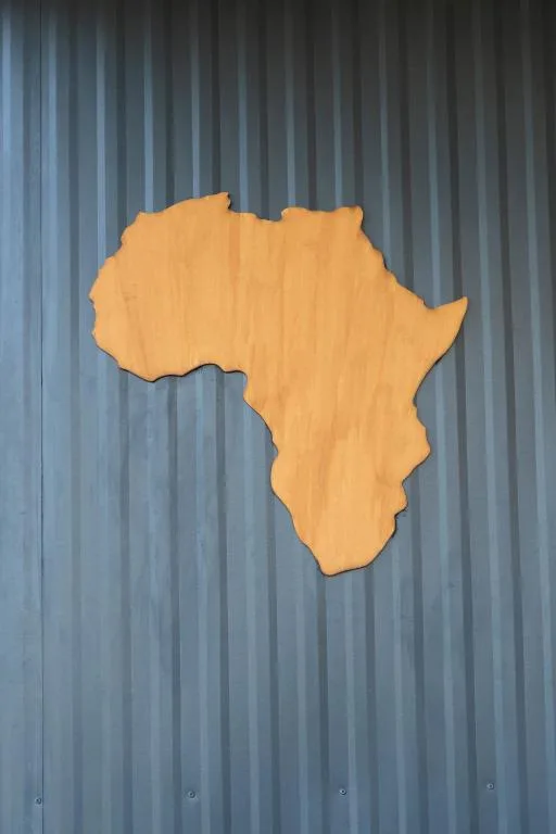 Yellow Africa map cutout mounted on corrugated metal wall