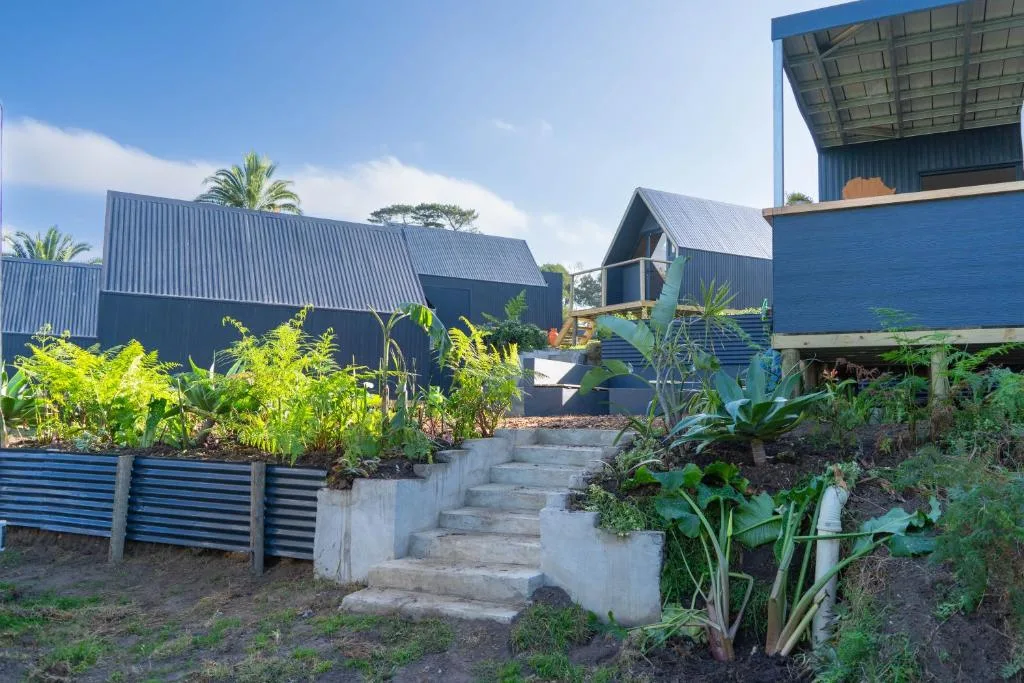 Modern blue corrugated metal glamping units with garden beds and steps