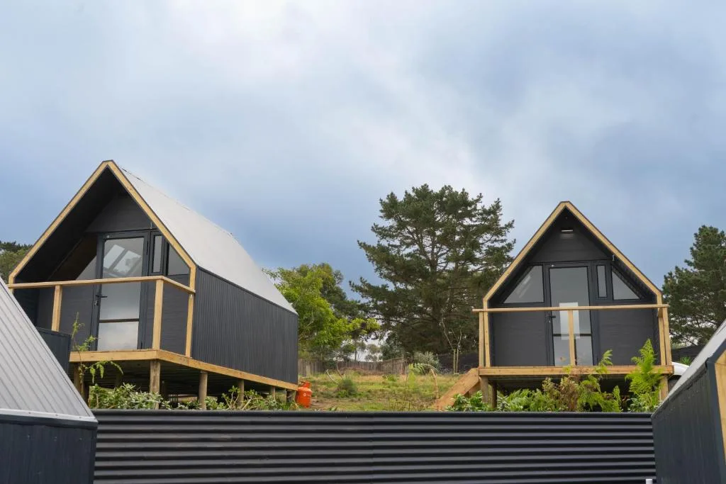 Two modern black glamping cabins with wooden frames and pitched roofs