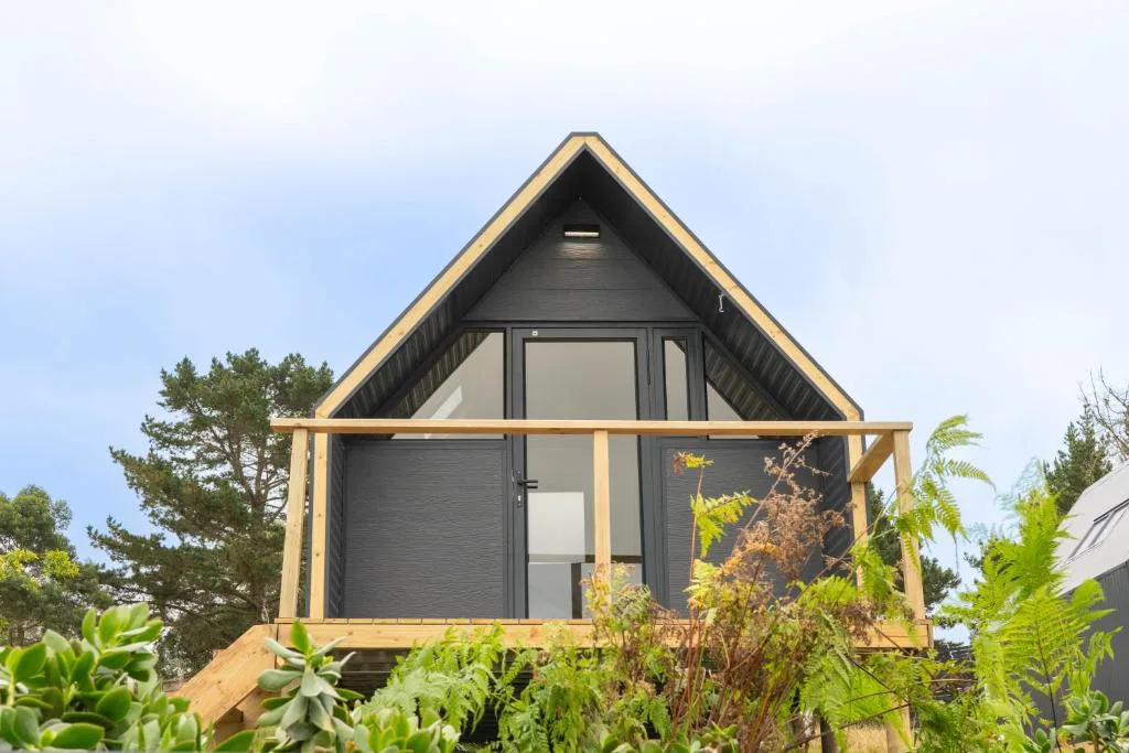 Modern A-frame glamping cabin with wooden deck and large windows
