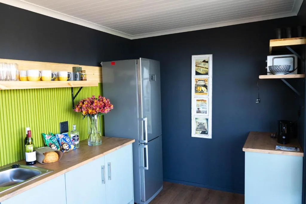 Modern kitchen with stainless steel fridge, white cabinetry, and green accent wall