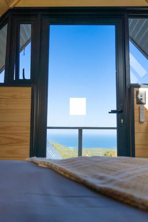 Ocean and coastal landscape visible through black framed glass doors