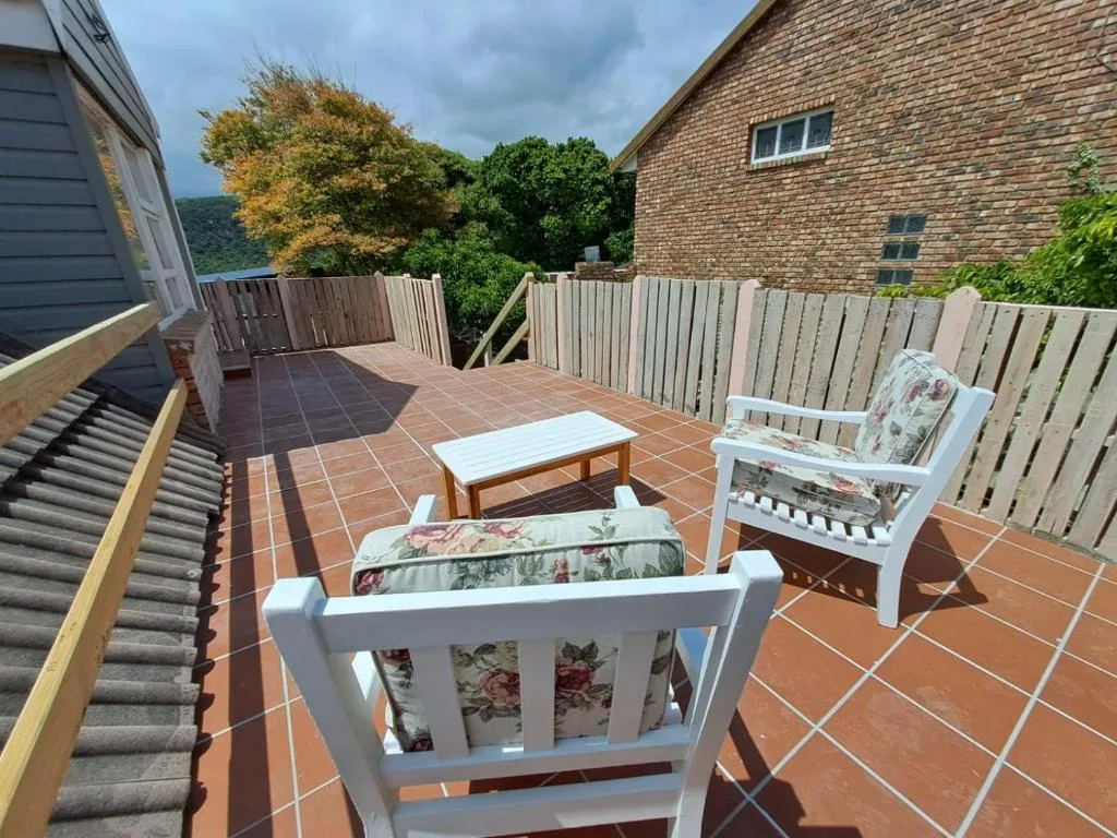 Spacious terracotta deck with white seating, wooden railing, and forested mountain views