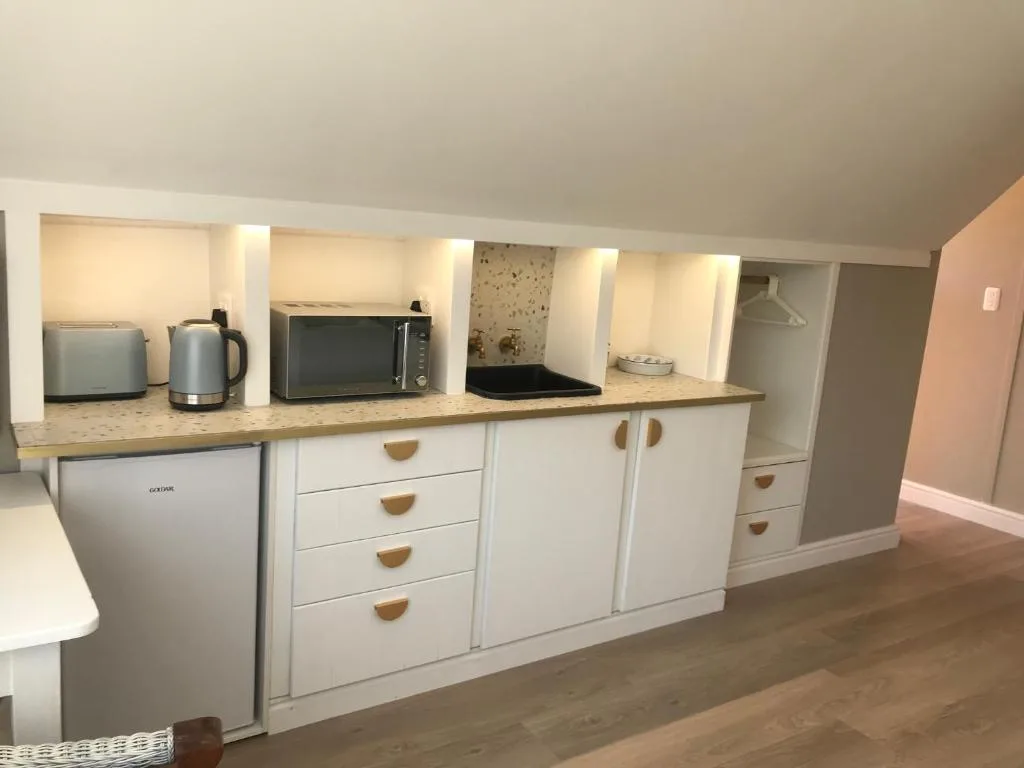 Modern kitchenette with white cabinetry, granite countertop, and integrated appliances