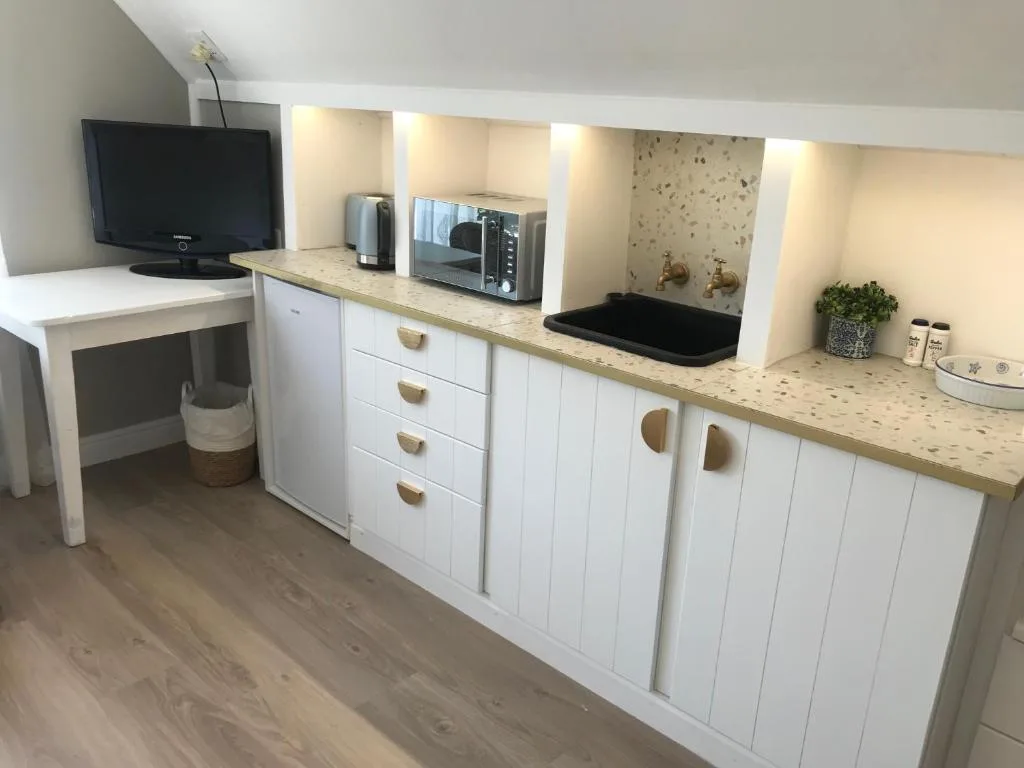 Modern white kitchen with granite countertops, appliances, and open shelving