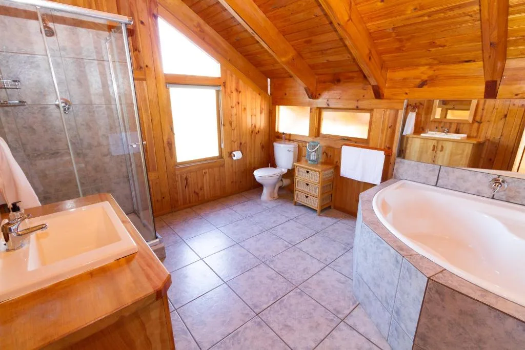 Spacious wooden bathroom with shower, toilet, dual sinks, and soaking tub