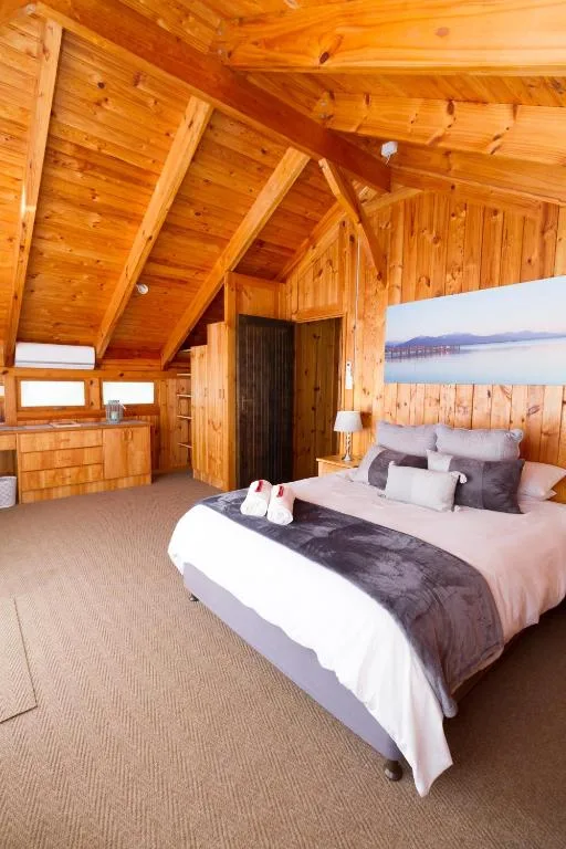 Spacious wooden bedroom with queen bed and water view artwork