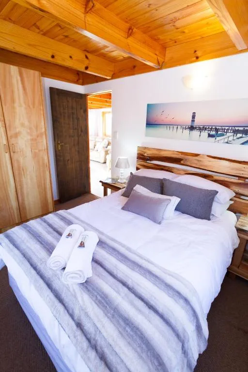 Spacious bedroom with wooden ceiling beams and natural light throughout