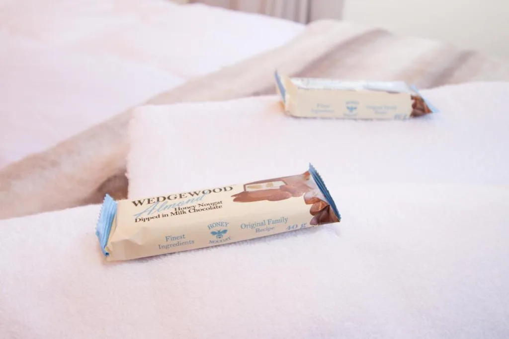 Complimentary chocolates placed on a neatly made bed with white linens