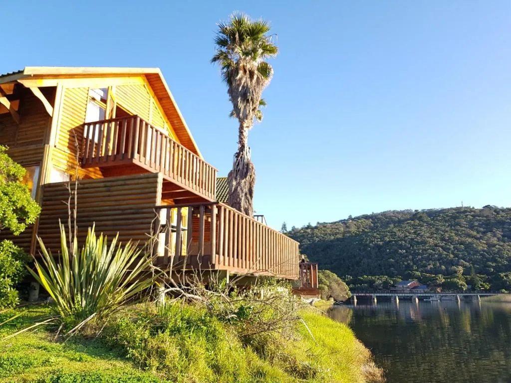 Wooden chalet with deck overlooking lagoon and lush hillside vegetation
