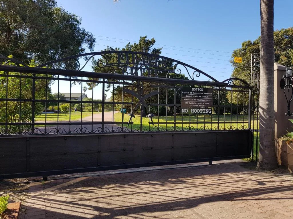 Ornate black metal driveway gate with manicured grounds beyond