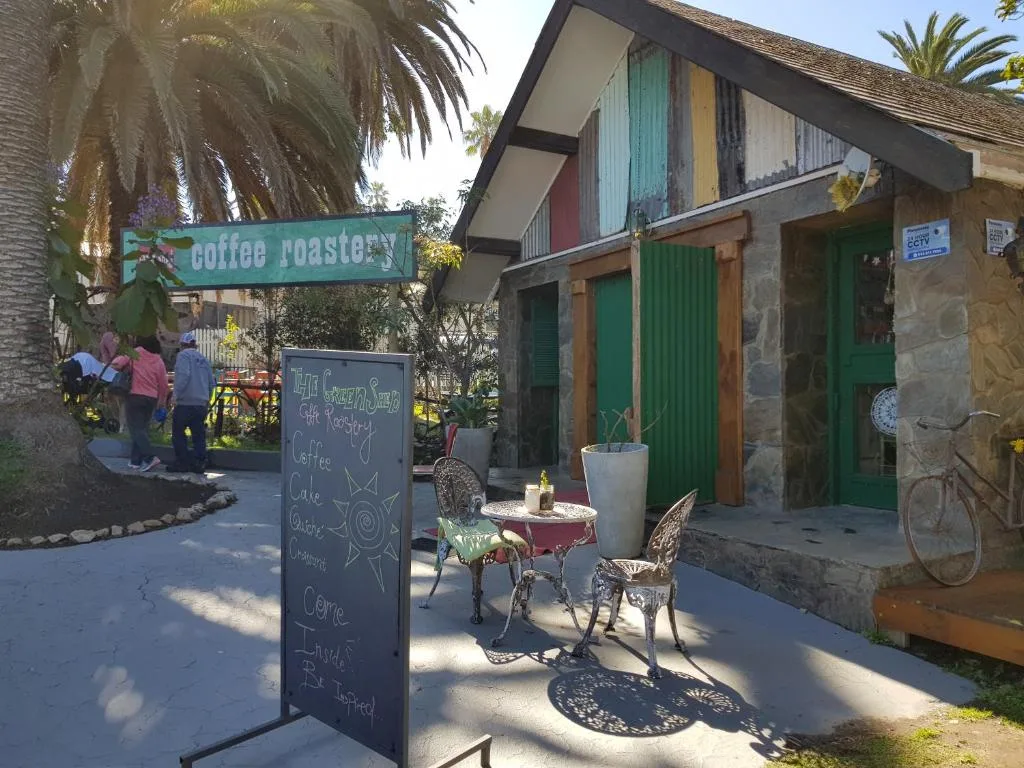 Colorful chalet exterior with green doors and palm tree garden setting