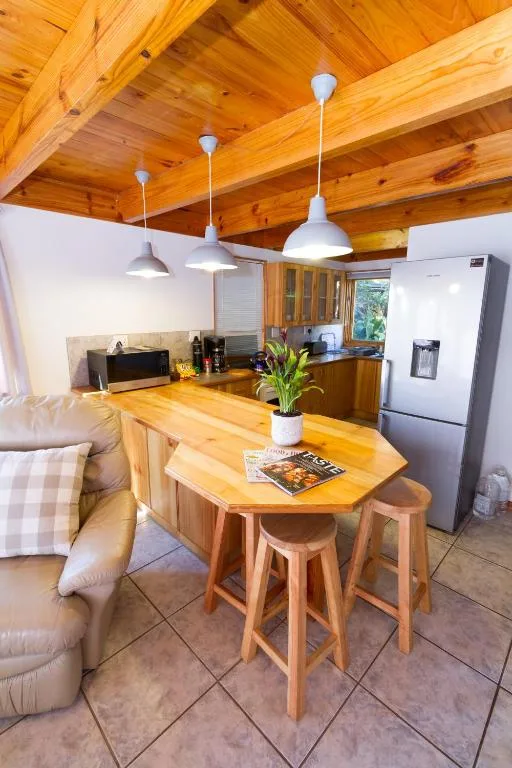 Open-plan kitchen with wooden beams, pendant lights, and island counter