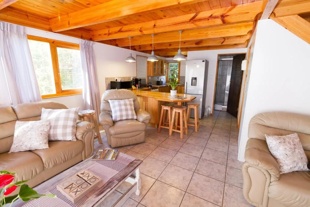 Open-plan lounge with cream leather sofas and exposed wooden beams