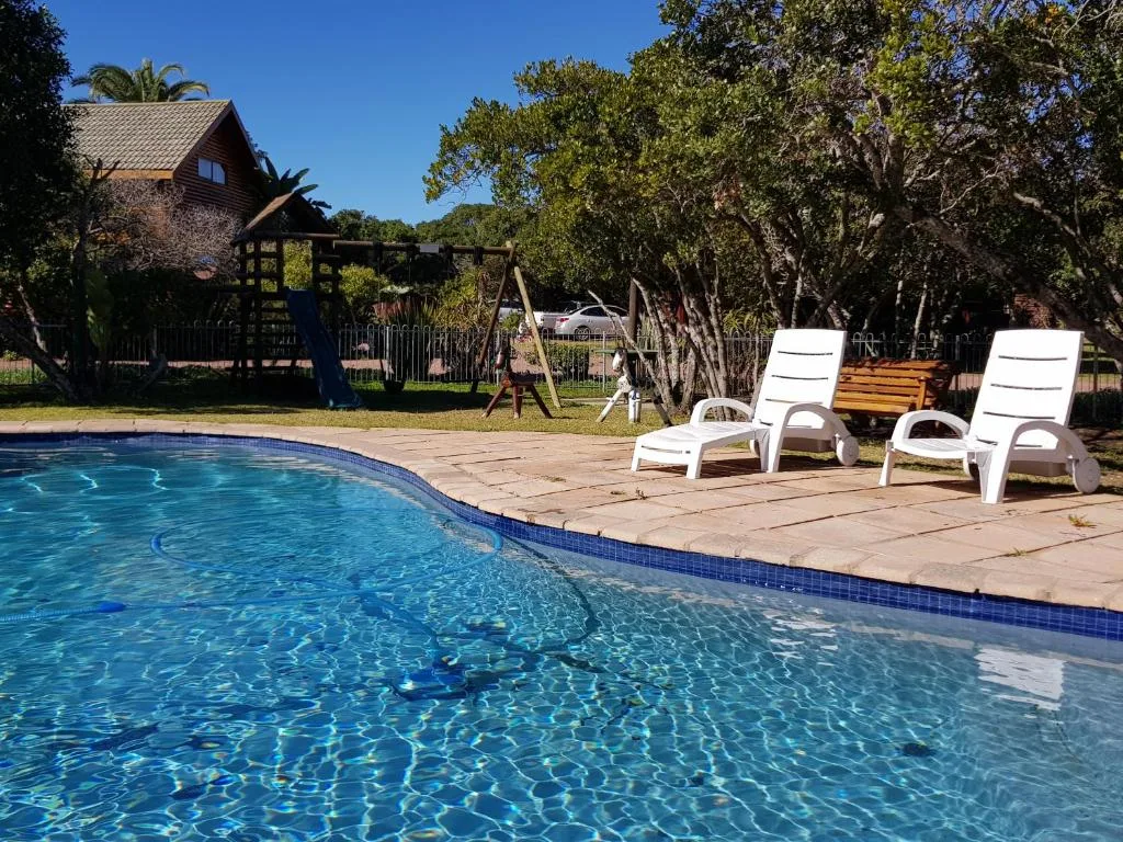 Sparkling swimming pool with loungers and property in background