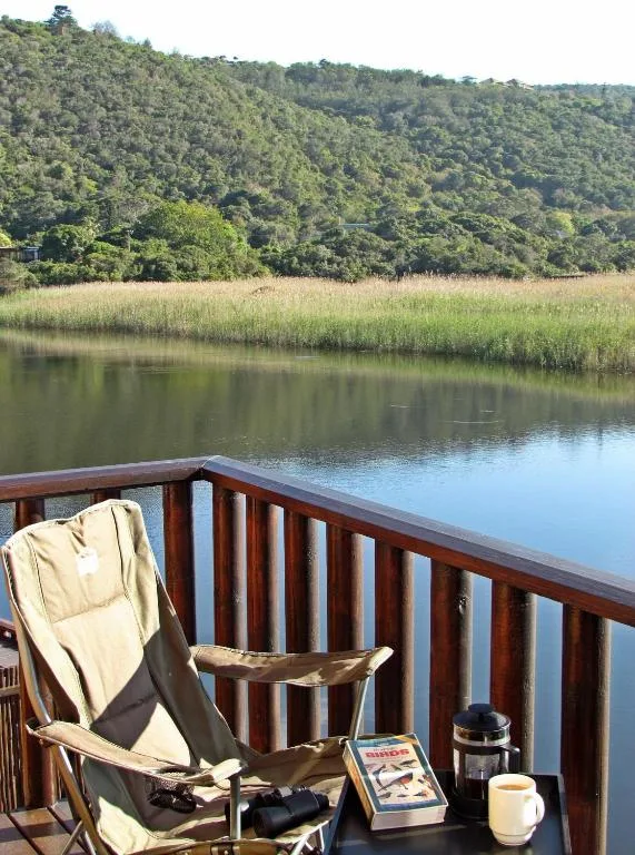 Tranquil lagoon view with lush green hillside and reed beds beyond