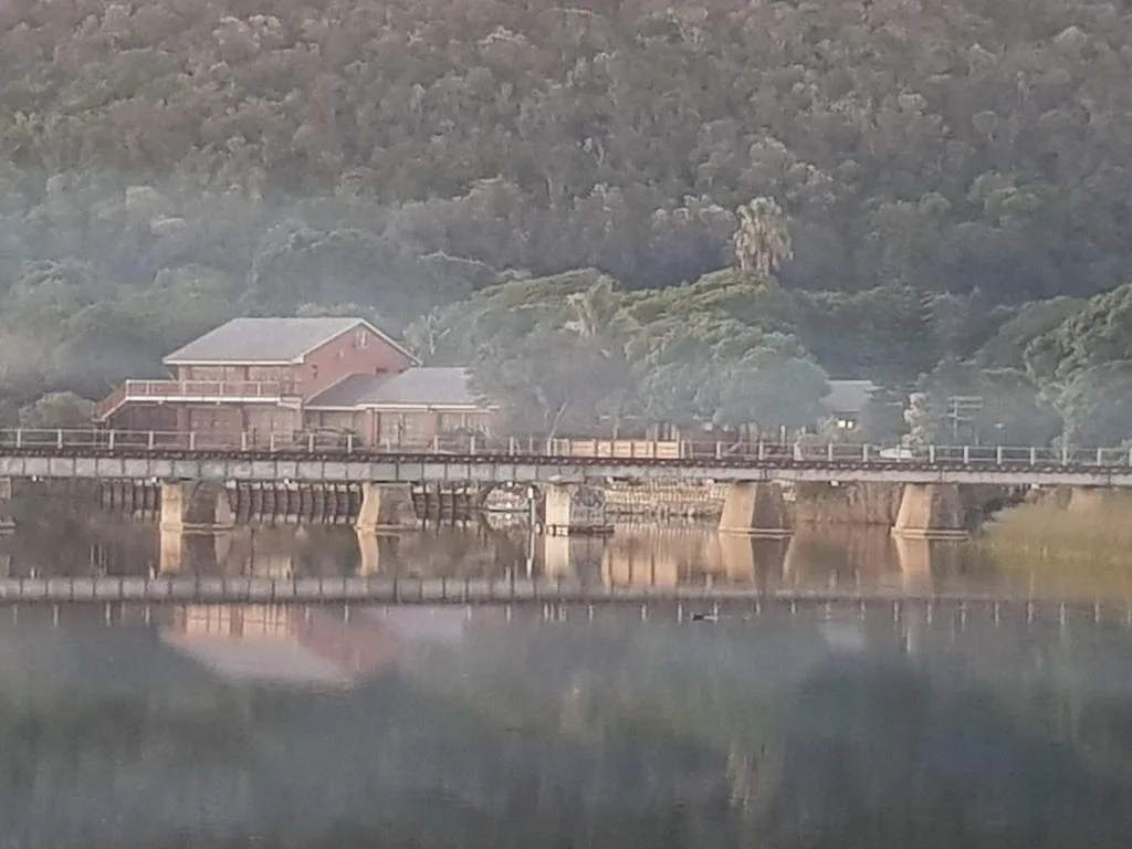 Waterfront property with misty forested hills reflected in calm lagoon