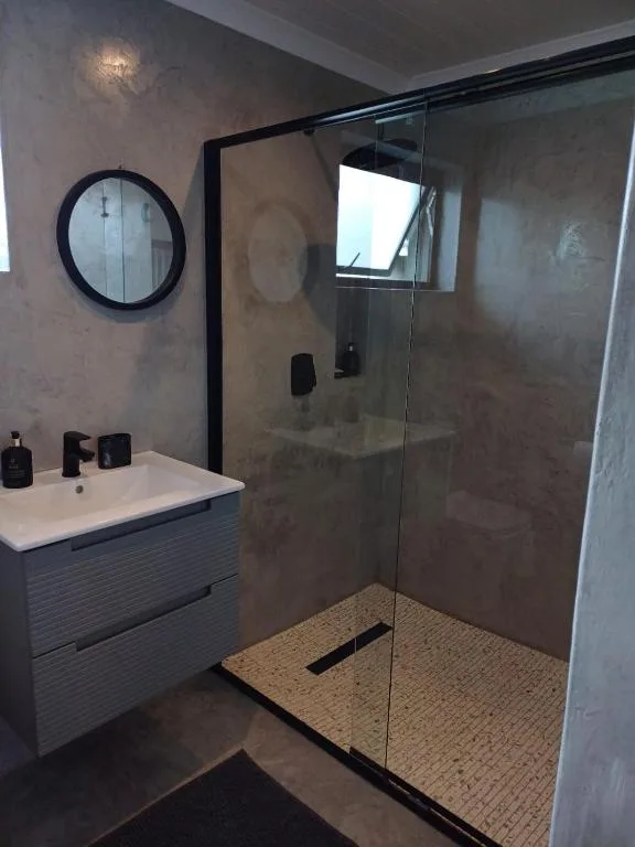 Modern bathroom with walk-in shower, vanity sink, and round mirror