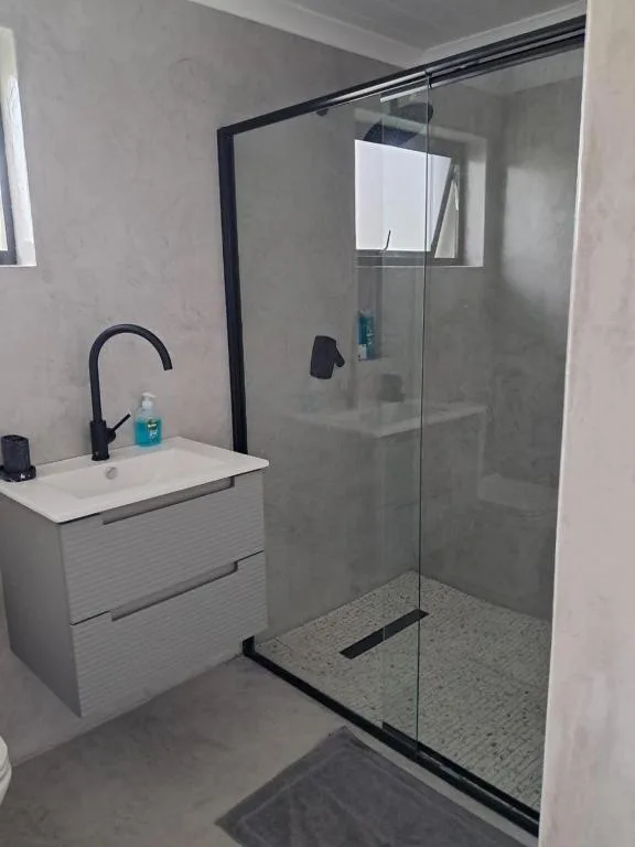 Modern bathroom with white vanity, black tap, and glass-enclosed shower