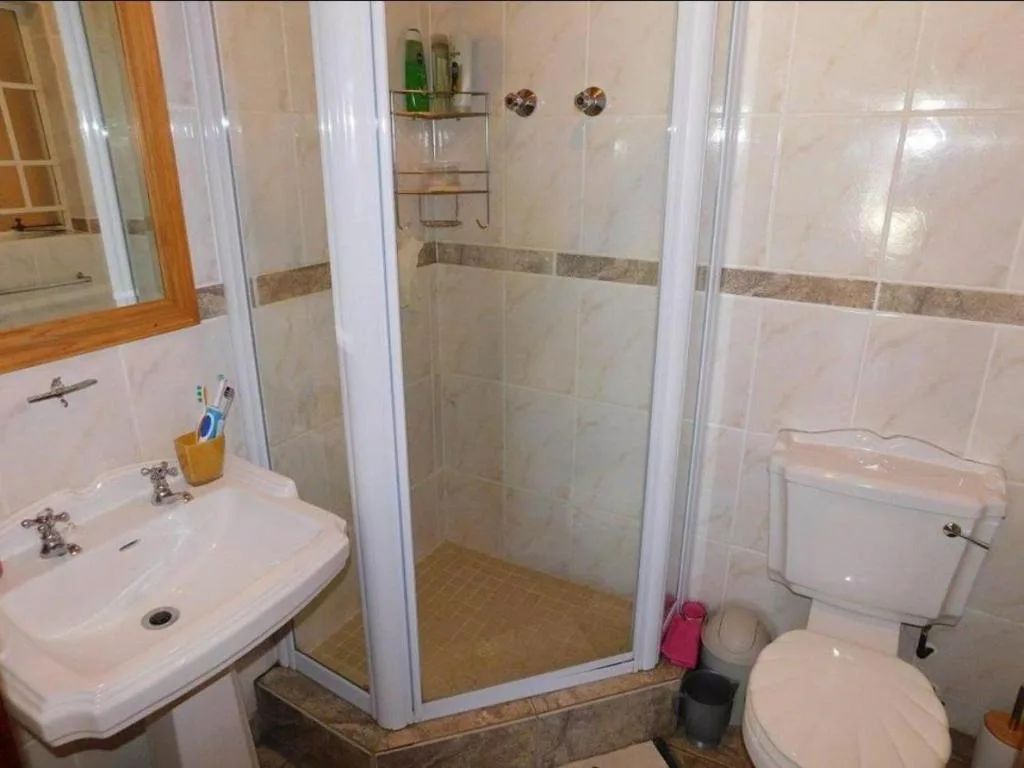Clean bathroom with vanity sink, enclosed shower cubicle, and toilet
