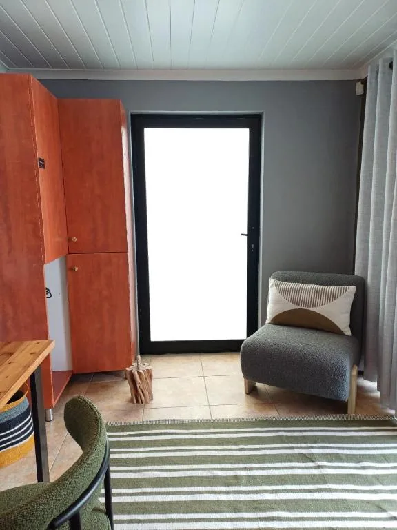 Compact bedroom with single bed, red wardrobe, and glass door access