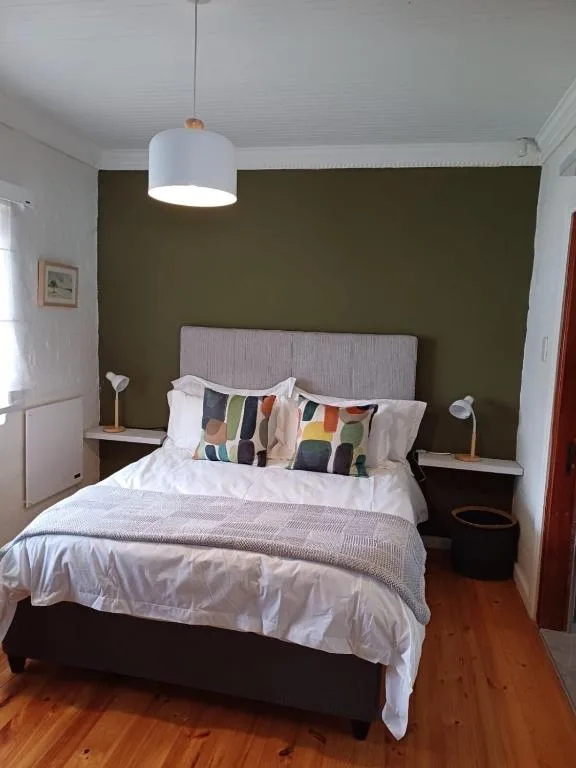 Modern bedroom with queen bed, olive accent wall, pendant lighting