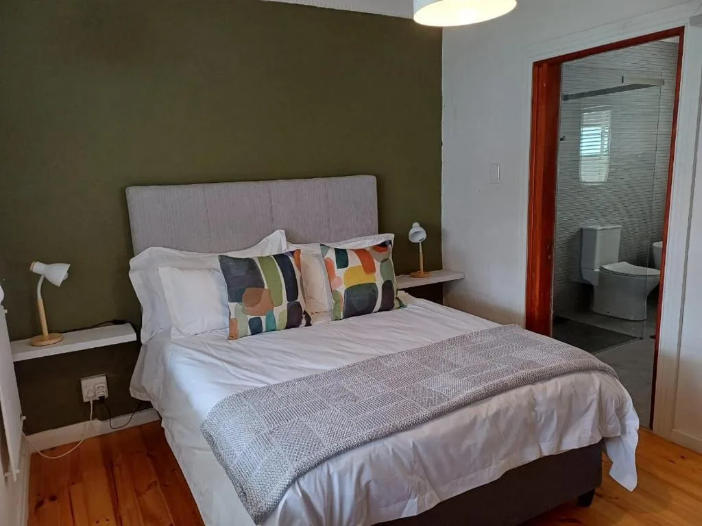 Spacious bedroom with queen bed, colorful pillows, and ensuite bathroom access