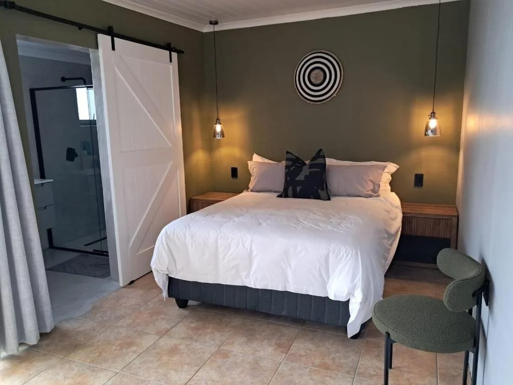 Modern bedroom with queen bed, pendant lighting, and ensuite bathroom access