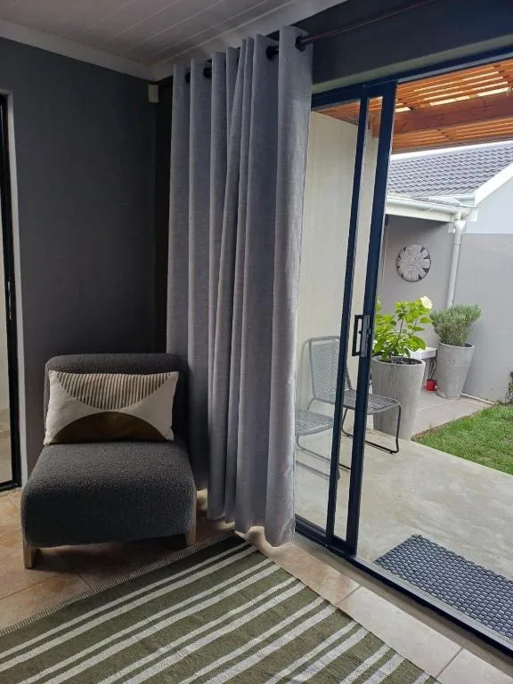 Modern patio with seating chair, potted plants, and garden access
