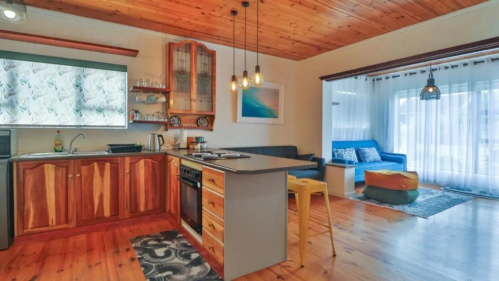 Open-plan kitchen with wooden cabinetry, island counter, and pendant lighting