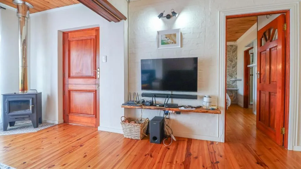 Spacious lounge with flat-screen TV, fireplace, and wooden flooring throughout