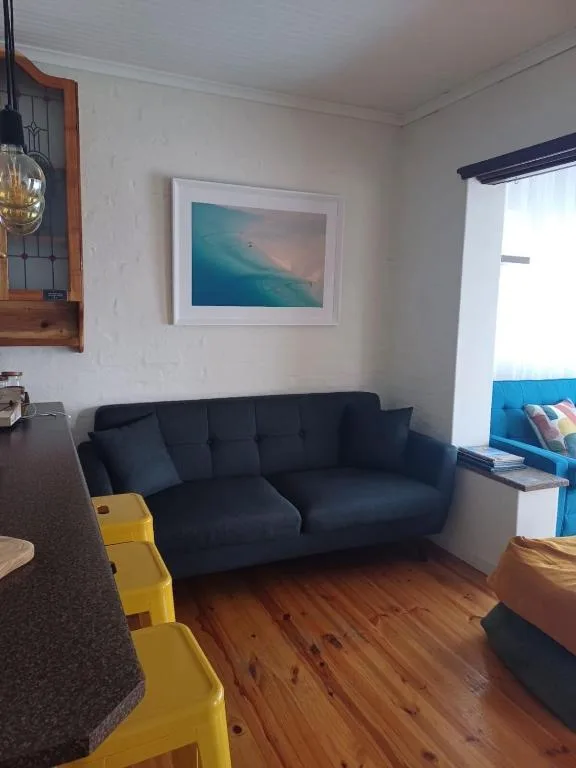 Modern lounge with dark sofa, wooden floors, and coastal artwork